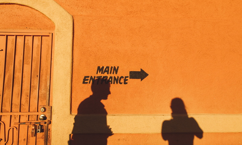 built structure, arrow, women, men, person, man, building exterior, orange color, lifestyles, wall, painted, focus on shadow, three quarter length, wall - building feature