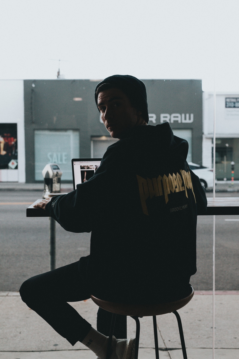 5K, real people, sitting, coffee shop, laptop, leisure activity, holding, stool, lifestyles, rear view, chair, beanie hat, silouette, using, wireless technology