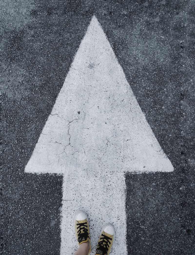 day, marking, low section, road, sign, body part, limb, arrow, real people, human body part, shoe, high angle view, direction, human foot, one person, human limb