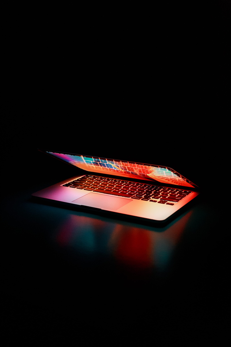 single object, turned, contemporary, 5K, studio shot, design, illuminated, macbook pro, colored background, glowing, technology, opened, internet, reflection