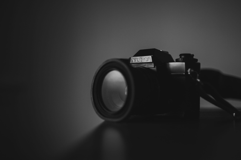 slr camera, focus on foreground, table, photographic equipment, digital camera, new, toy, photo, black and white, grayscale, retro Styled, old-fashioned