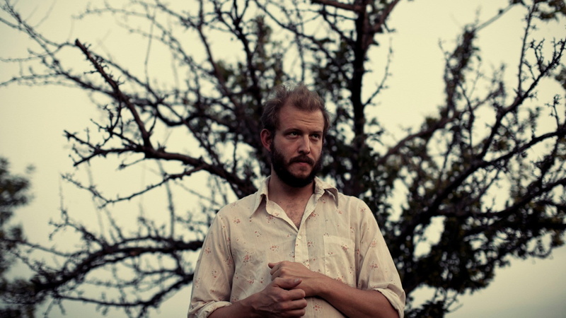 young adult, nature, front view, adult, standing, outdoors, real people, bon iver, waist up, hairstyle, lifestyles, focus on foreground, plant, looking at camera