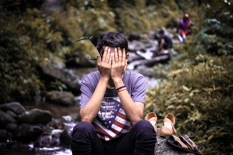 lifestyles, young adult, rock, men, outdoors, rock - object, sitting, leisure activity, facepalm, day, forget, focus on foreground, young, front view, three quarter length