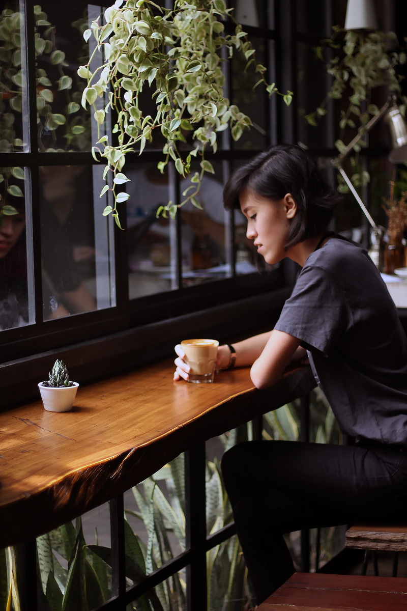 plant, cafe, hot drink, mug, table, hairstyle, adults only, seat, counter, one Woman Only, females, leisure activity, drink, lifestyles, women, looking