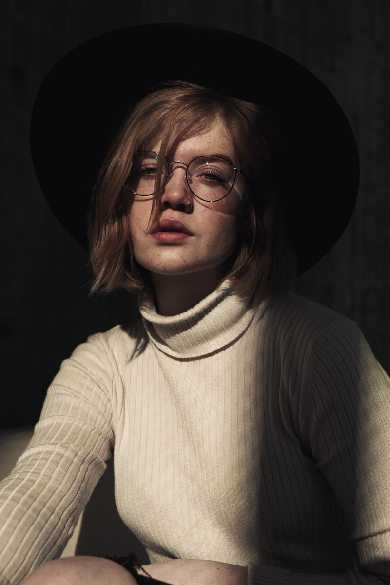 looking at camera, accessory, beside, 4K, sitting, accessories, person, sun hat, wall, face, hairstyle, photo, human, clothing, man, sweater, young adult
