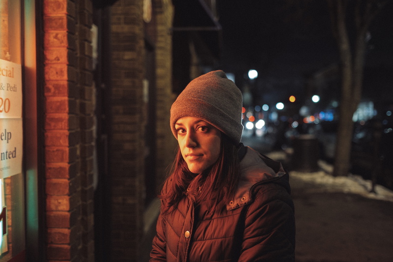 looking at camera, clothing, night, woman, female, city, light, hat, architecture, one person, building, lady, black, leisure activity, young women, orange
