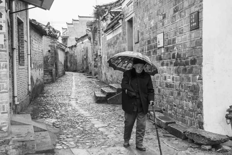 building exterior, building, transportation system, cane, built structure, protection, real people, alley, walking, man, pavement, grayscale, old lady