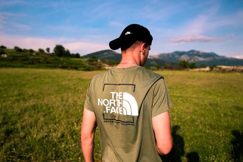 the noth face, t-shirt, cap, rom, apparel, western script, face, uniform, summer, brown, plant, one person, occupation, human, government, land, photo