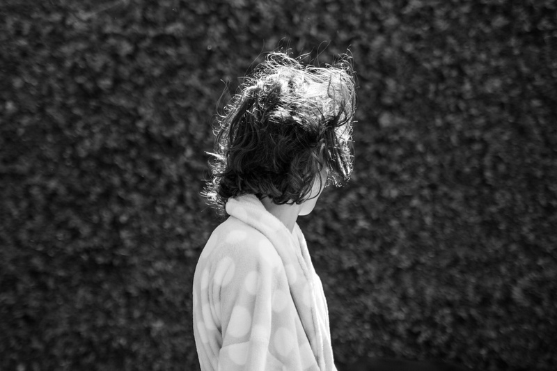 messy hair, real people, outdoors, sun, faceless, focus on foreground, 5K, waist up, side view, black and white, anonymous, child, leisure activity, empty