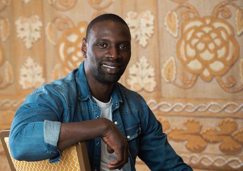 young adult, emotion, leisure activity, smiling, one person, lifestyles, happiness, front view, looking at camera, omar sy, real people, waist up, standing
