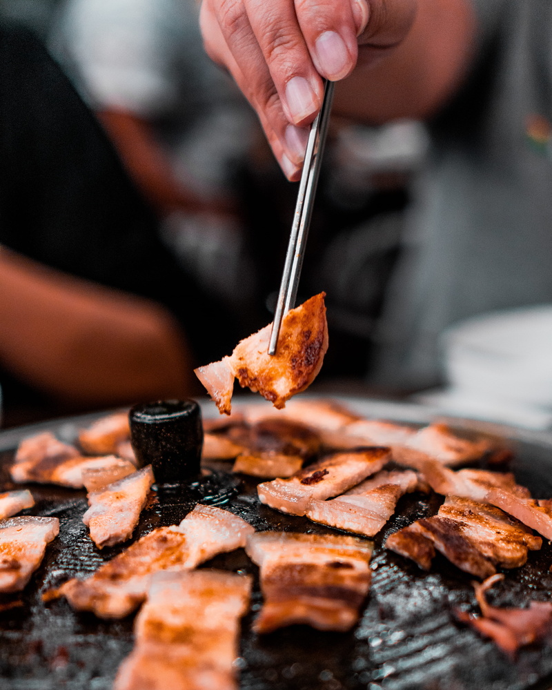 chopsticks, steak, person, cafeteria, sushi, sticks, chef, hot dog, finger, food, cooking, eating utensil, hand, focus on foreground, selective focus, grill