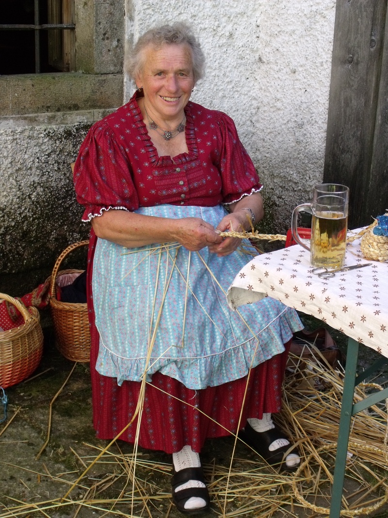 outdoors, full length, 2K, hairstyle, costume, straw, container, old craft, holding, adult, senior women, chair, looking at camera, portrait, table, rural life