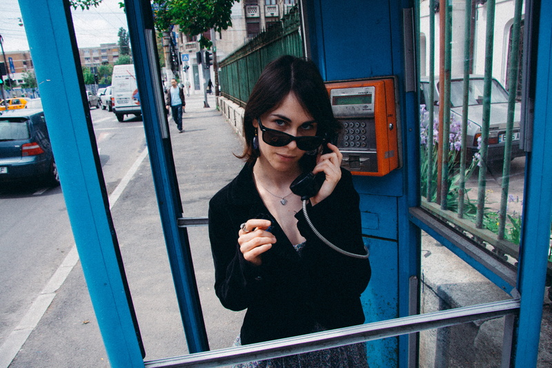 cheerful, front view, smiling, phone booth, beautiful woman, young women, urban Scene, telephone, city Life, business, technology, sunglasses, waist up