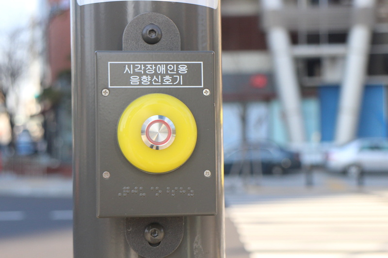 close-up, pole, button, street, building exterior, yellow, no people, sign, control, blind, focus on foreground, sound alarms, text, outdoors, communication