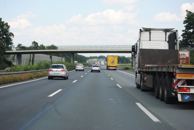 street, land vehicle, cloud - sky, ride, side, sign, semi-truck, outdoors, on the move, car, travelling, day, motor vehicle, sky, asphalt, road, transport of goods