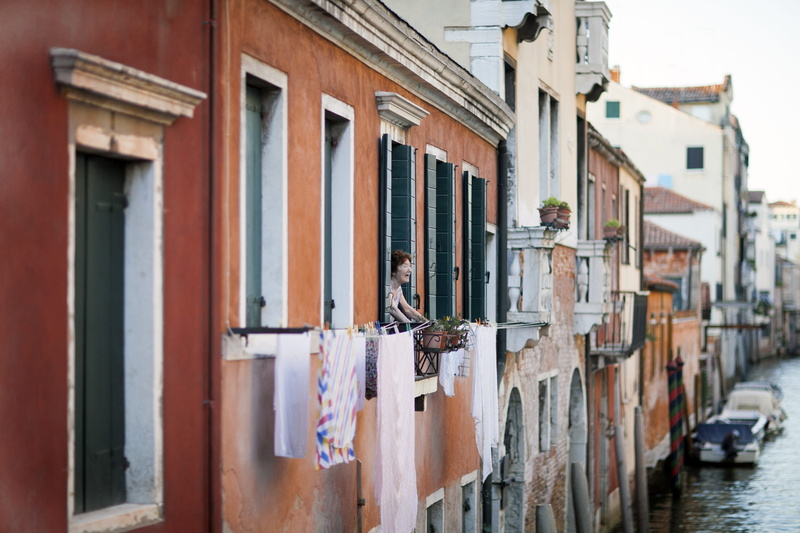 daytime, washing, built structure, clothing, hanging, row house, clothesline, drying, balcony, person, water, building, wood - material, alley, window