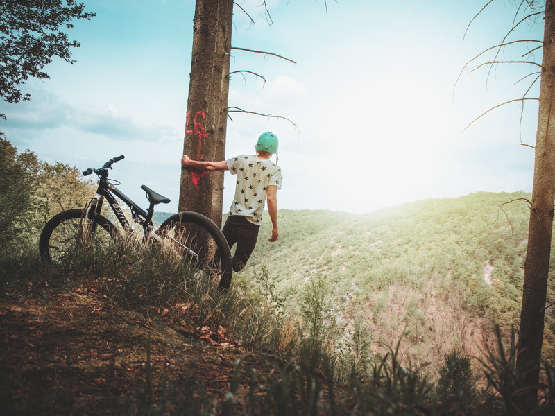 bicycle, land vehicle, wheel, grass, helmet, environment, travel, portrait, growth, day, recreation, seat, extreme sport, holding, view, mode of transportation