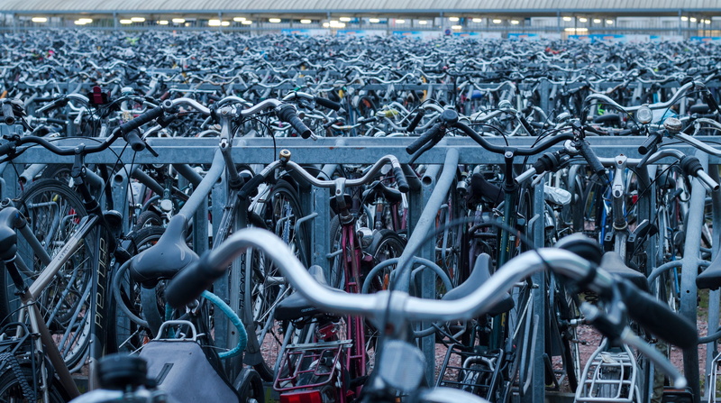 wheel, focus on background, many, parking lot, bicycle, rows, mode of transportation, land vehicle, bicycle rack, bicycles, no people, day, steel, outdoors