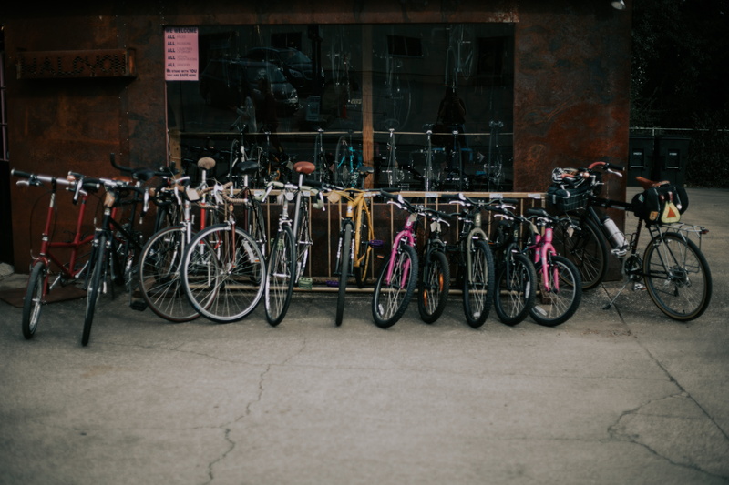 in a row, incidental people, building, road, parking, shop, daytime, people, kids bike, land vehicle, architecture, transportation, bicycle, city street