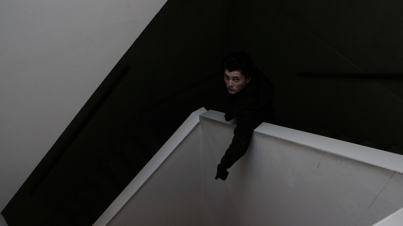 steps and staircases, looking at camera, man, cubicle, night, emotion, men, headshot, one person, young adult, 5K, indoors, front view, high angle view