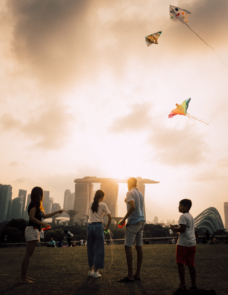 kid, playing, flying, fun, grass, men, field, people, young, group Of People, sunset, lifestyles, sport, child, sky, four, park, city, kite, skyscraper
