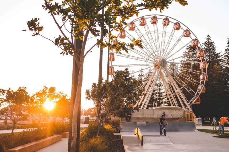 group of people, built structure, outdoors, amusement park, incidental people, men, tree, fairground, bike, theme park, nature, sunrays, leisure activity