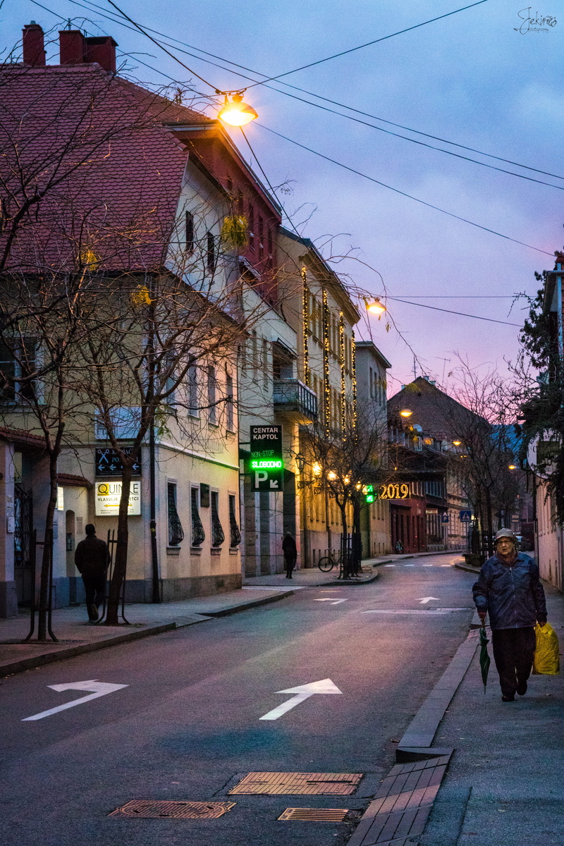 person, direction, road marking, illuminated, residential district, building, sky, pedestrian, street, zebra crossing, path, nature, built structure, asphalt
