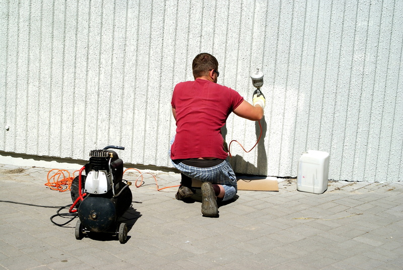 outdoors, employee, paint, wall, standing, men, poland, renewals, casual clothing, gun, people, leisure activity, full length, man, young adult, young men
