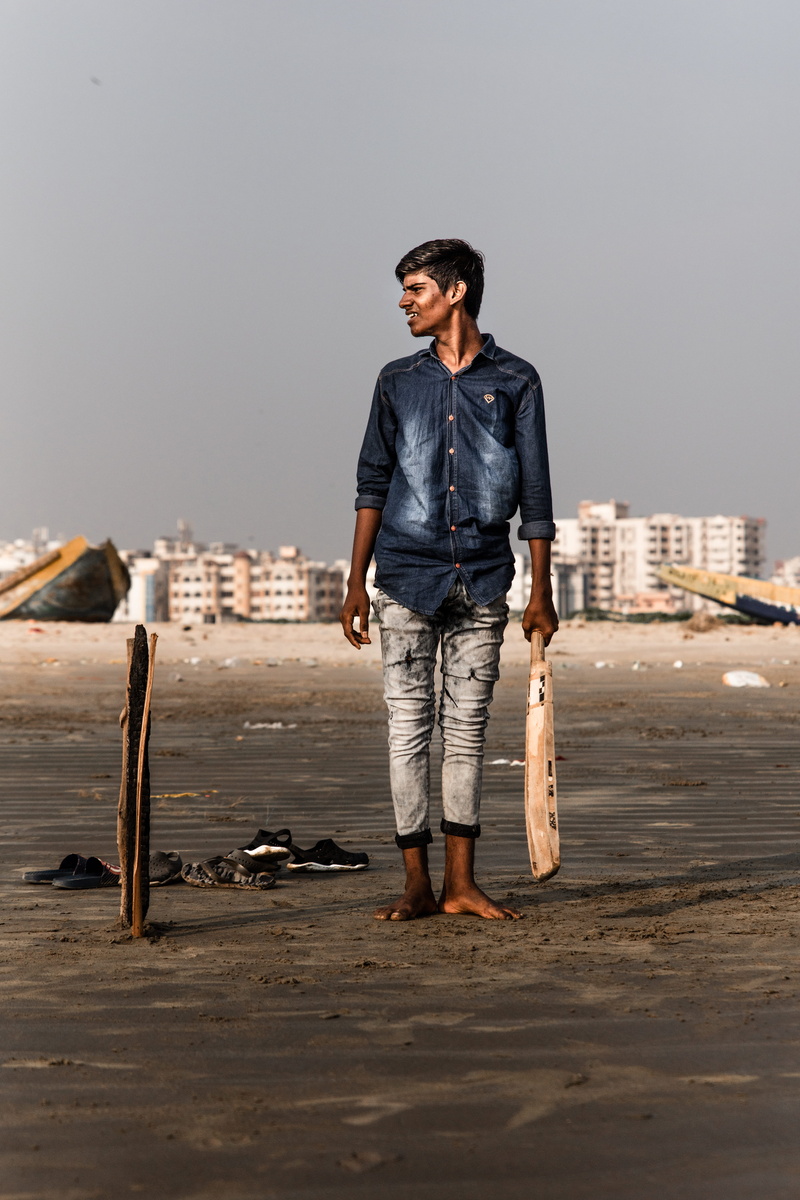 one person, right, daytime, side, glasses, cricket, jeans, man, real people, front view, looking away, outdoors, architecture, looking, standing, 8K, smiling