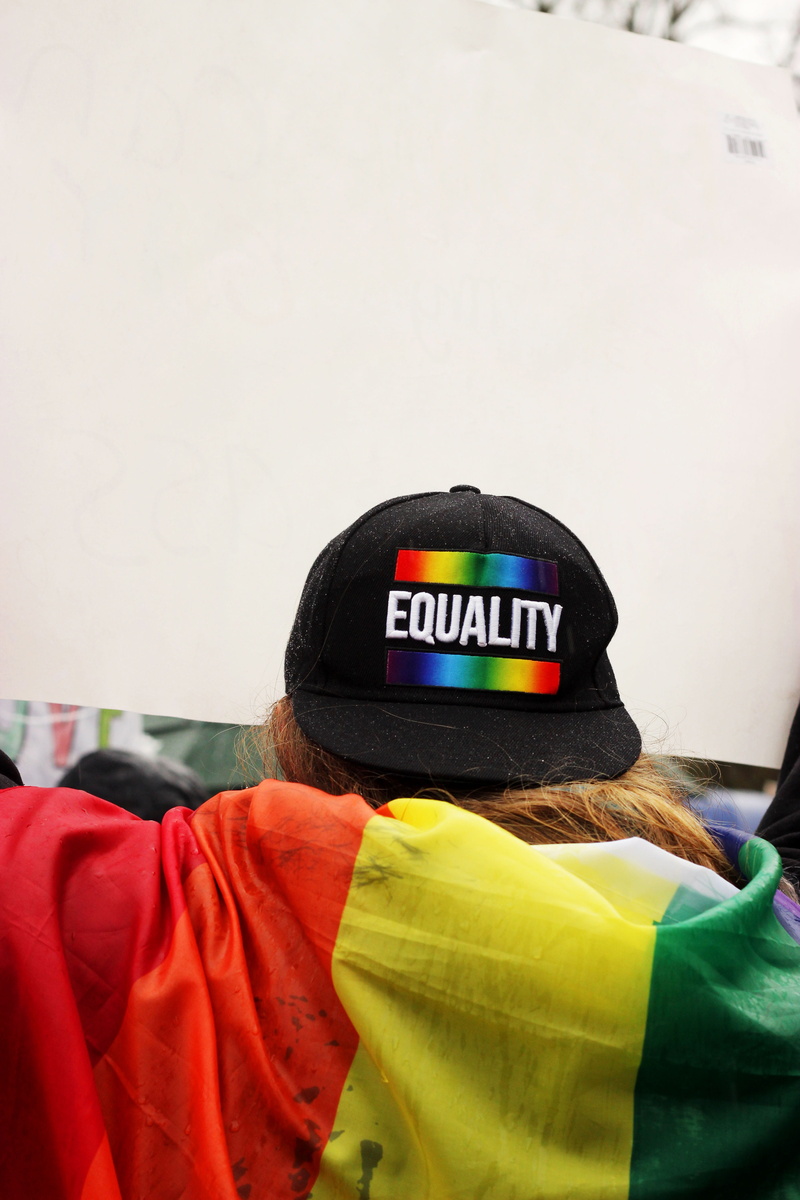 beanie, western script, lgbt, blanket, rainbow, person, obscured face, headshot, human, text, wearing, home decor, clothing, pride, equality, rear view