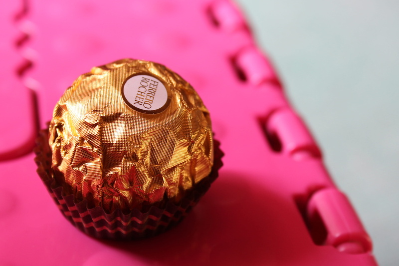 pink background, food and drink, golden, chocolate, technology, 2K, ball, still life, cup, no people, metal, wealth, sphere, ferrero rocher, sweet, studio shot
