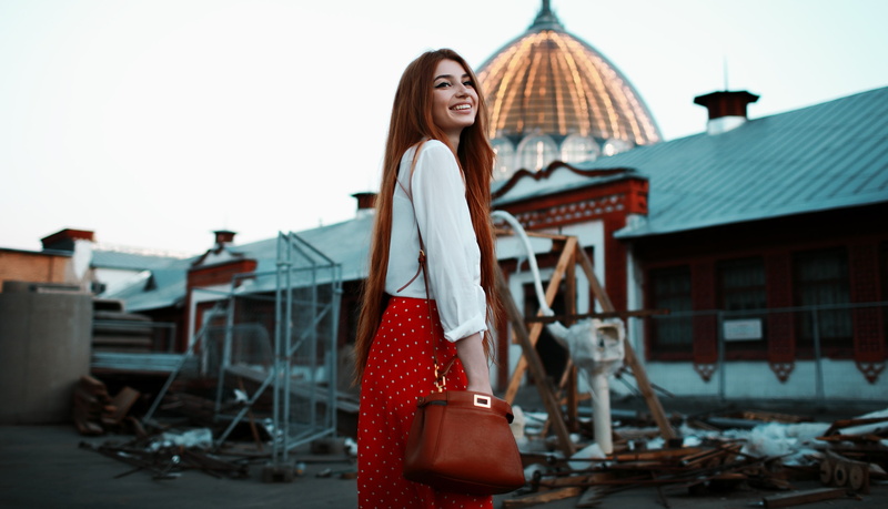 looking away, women outdoors, sky, redhead, depth of field, handbags, 2K, outdoors, shirt, building, model, smiling, women, skirt, long hair, portrait