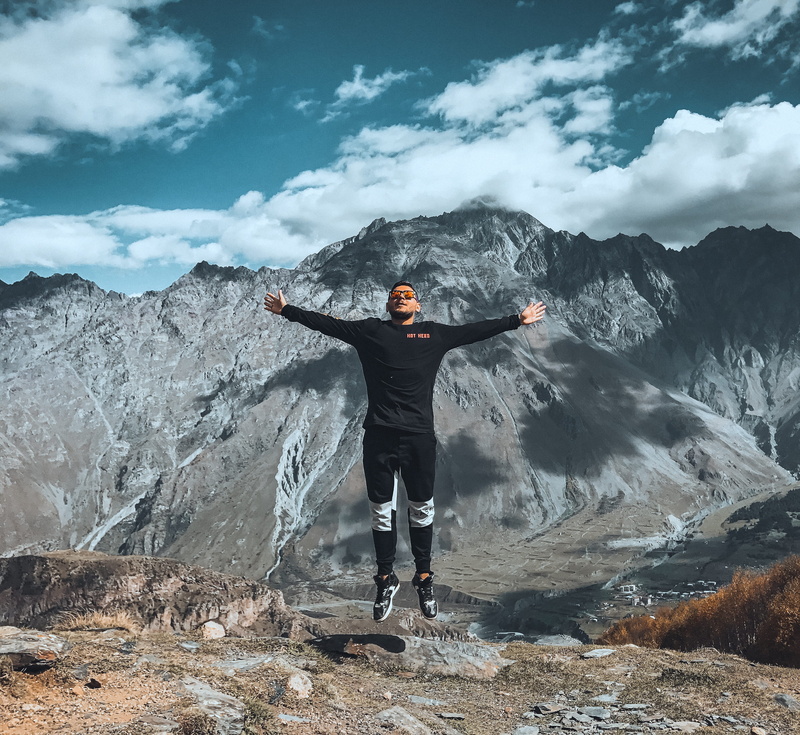 front view, human arm, lifestyle, air, blue, person, full length, action, 2K, one person, outdoors, travel, non-urban scene, male, arms raised, landscape