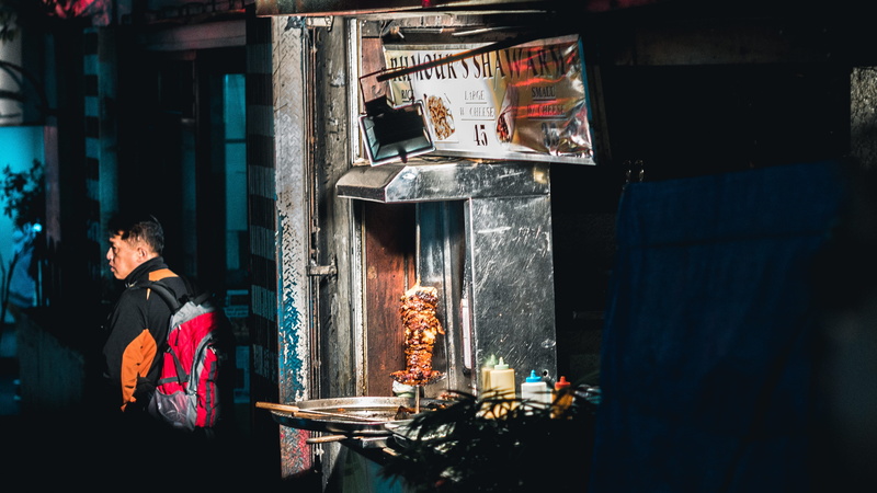 building, dark, standing, gyro, backpack, one person, outdoors, adult, architecture, near, retail display, occupation, market, wall, clothing, machine