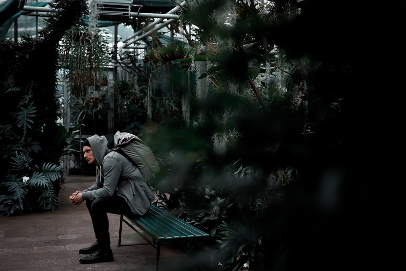young adult, plant, growth, shoe, apparel, footwear, sitting, adult, contemplation, casual clothing, greenhouse, person, tree, seat, clothing, photography