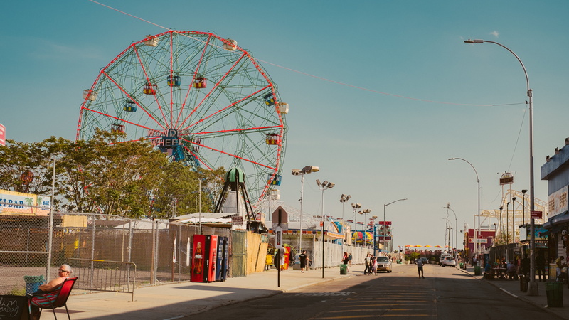 boardwalk, person, vehicle, downtown, sky, chair, town, amusement park ride, wheel, leisure activity, group of people, path, incidental people, arts culture and entertainment