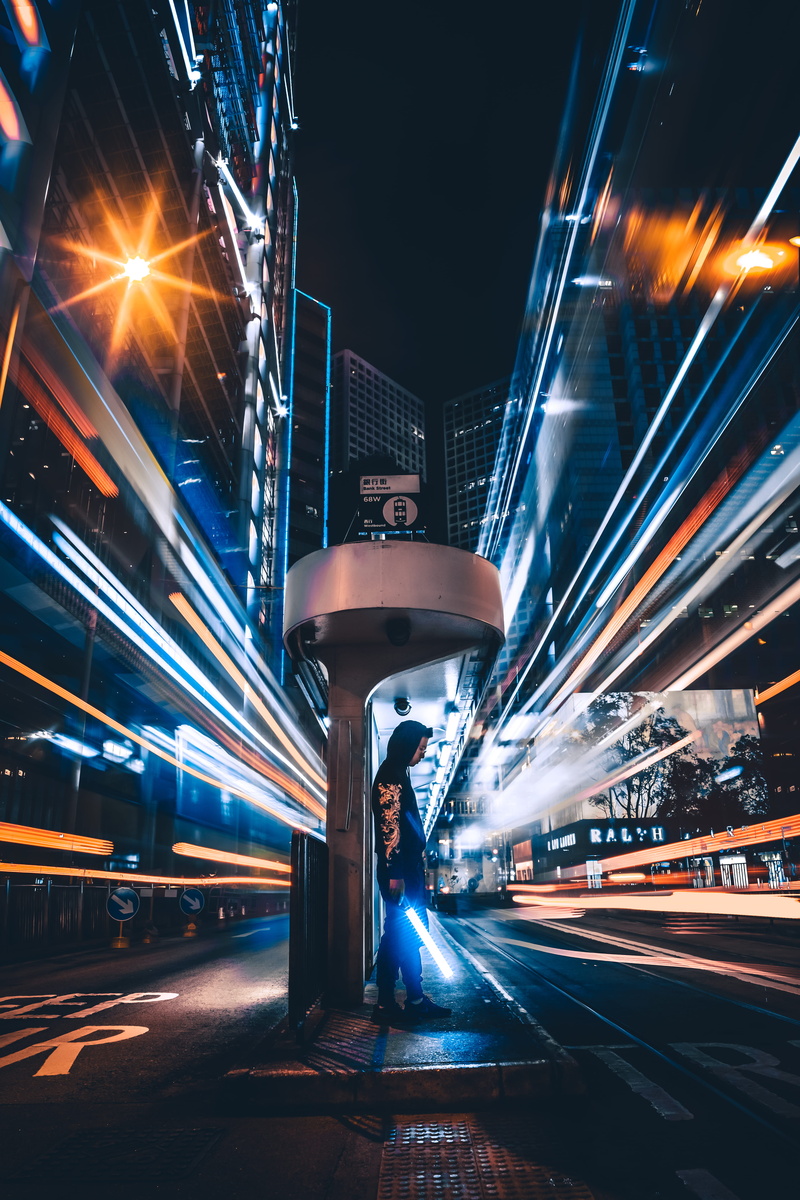 stop, outdoors, architecture, city, bus, built structure, standing, light trail, building exterior, transportation, one person, downtown, road, long-exposure