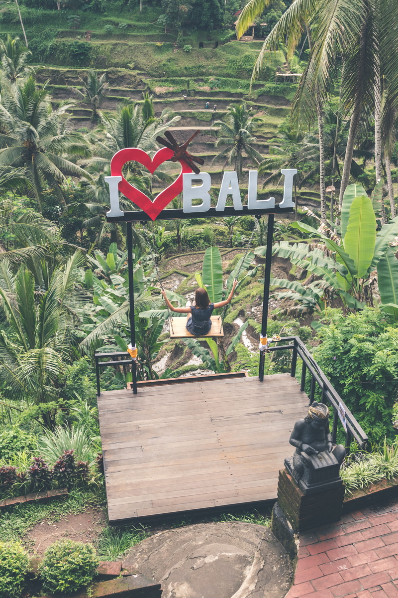 built structure, outdoors, bali, woman, growth, jungle, leisure activity, swing, person, green color, sign, information, wood - material, play, swinging