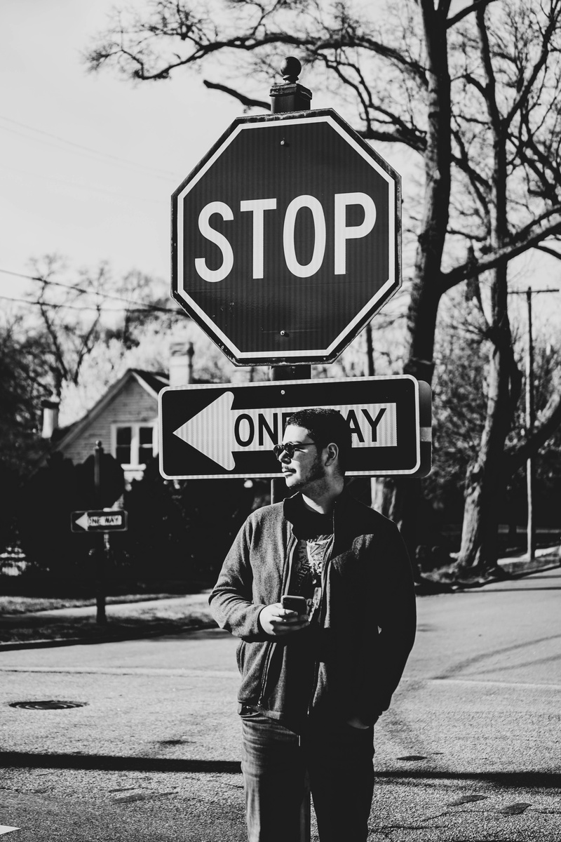 day, symbol, capital letter, road, sunlight, looking, people, casual clothing, stopsign, architecture, front view, directions, text, one person, person