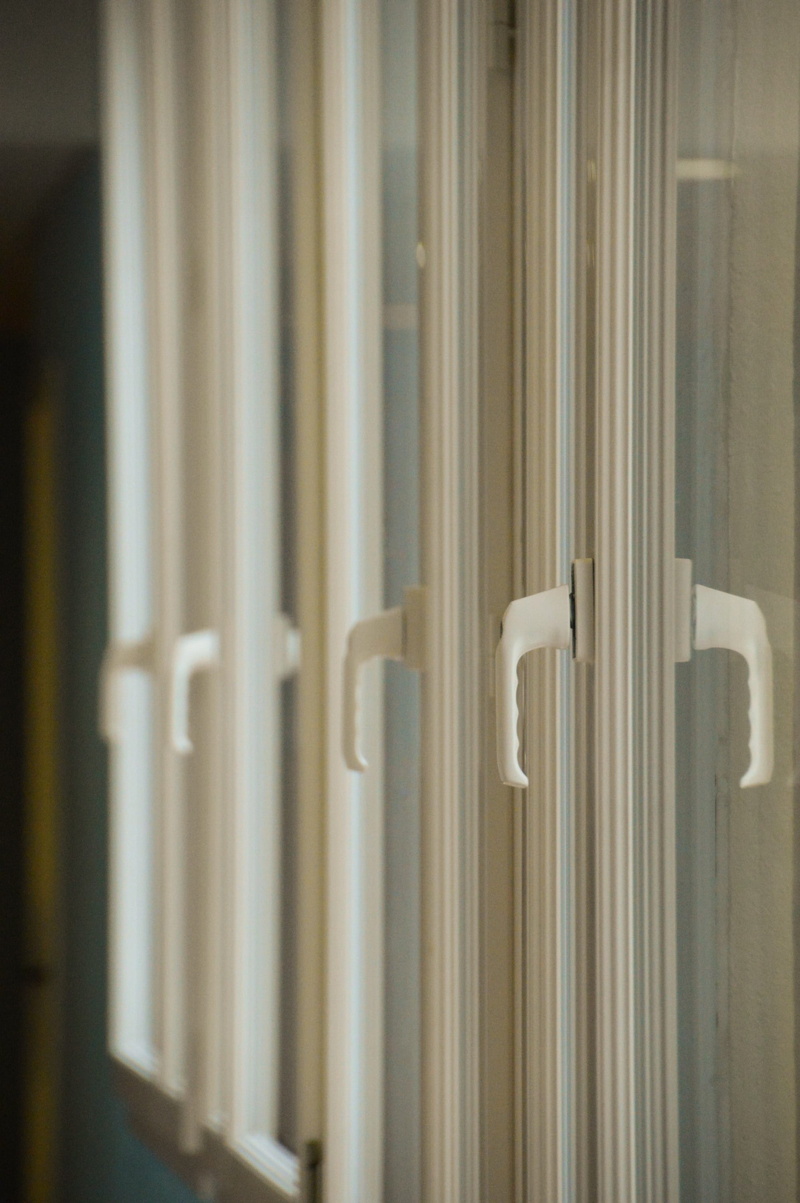 handle, white color, backgrounds, closure, indoors, day, coaching, focus on foreground, wood - material, plastic, repetition, insulation, window, metal