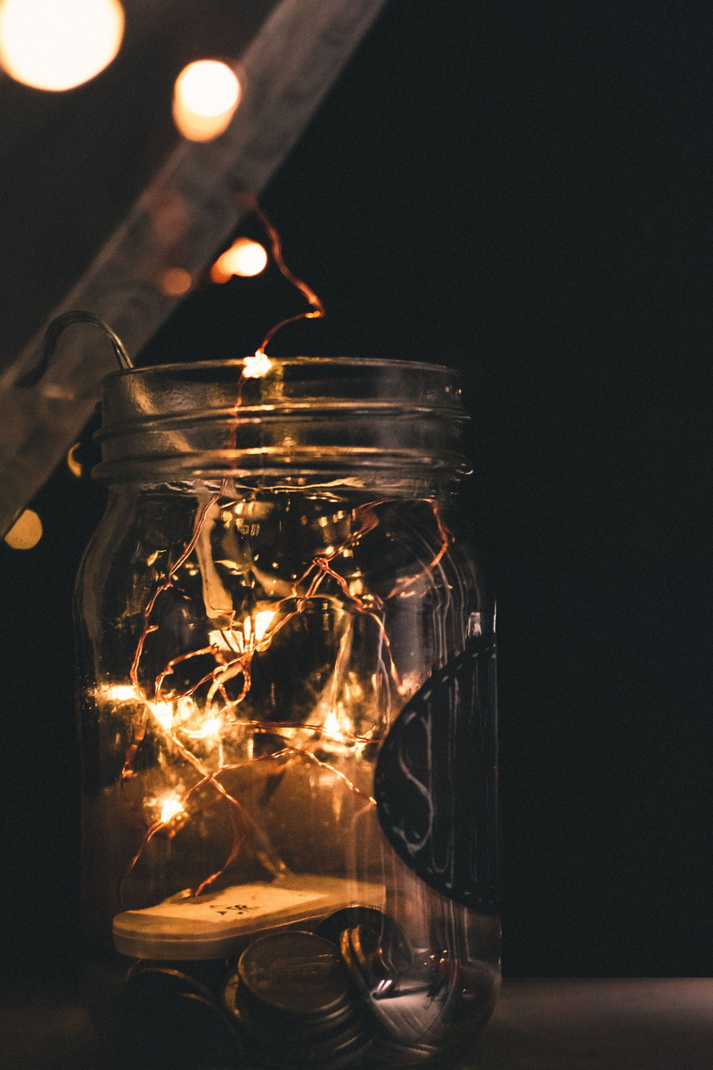 fire, indoors, flame, closeups, drink, reflection, fairylights, transparent, illuminated, focus on foreground, bokeh, sparks, glass, black background, lights