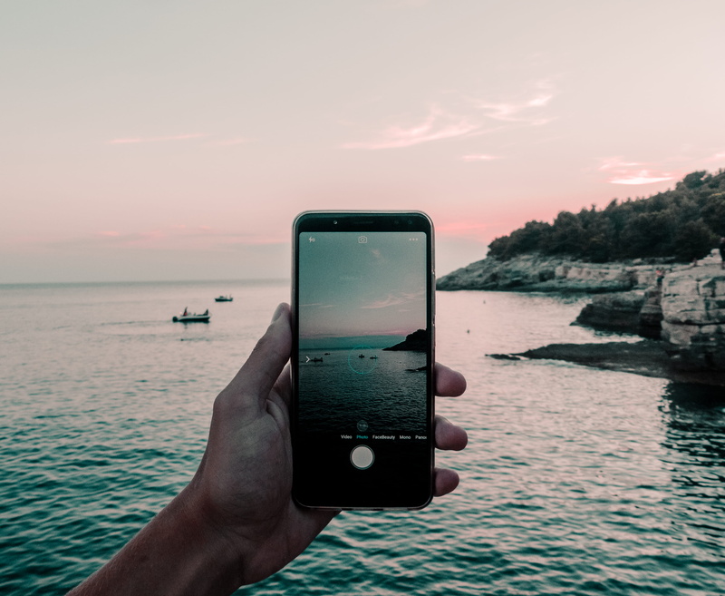 electronics, beach, body, outdoors, sunset, camera, cell phone, coast, water, mobile phone, photographing, scenics - nature, phone, technology, app, human hand