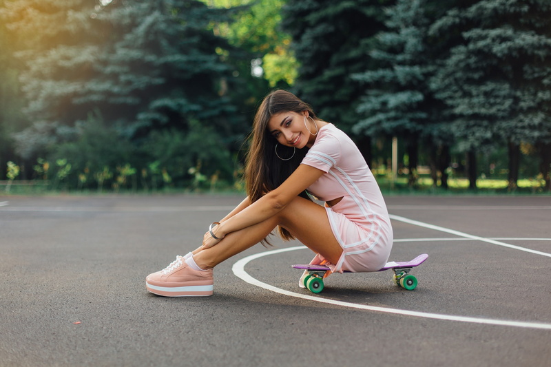 looking at viewer, sitting, brunette, depth of field, portrait, 2K, long hair, dress, smiling, women, skateboard, model, trees, hoop earrings, bracelets