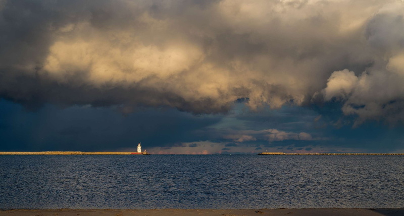 beach, ominous, seascape, horizon, sky, beauty in nature, tranquility, cloud - sky, maritime, landmark, lighthouse, dark skies, navigation, outdoors, scenic