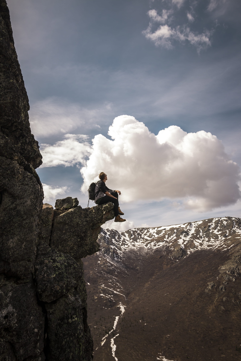 real people, nature, gray, on the edge, sitting, tranquil scene, cloud, hiker, extreme, cliff, beauty in nature, looking, hike, sky, boot, alaska, adventure