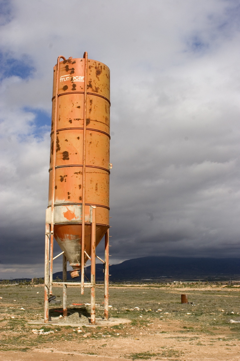 machine, field, built structure, water tower - storage tank, building exterior, cement, day, sky, horizon, outdoors, metal, technology, cloud - sky, industry