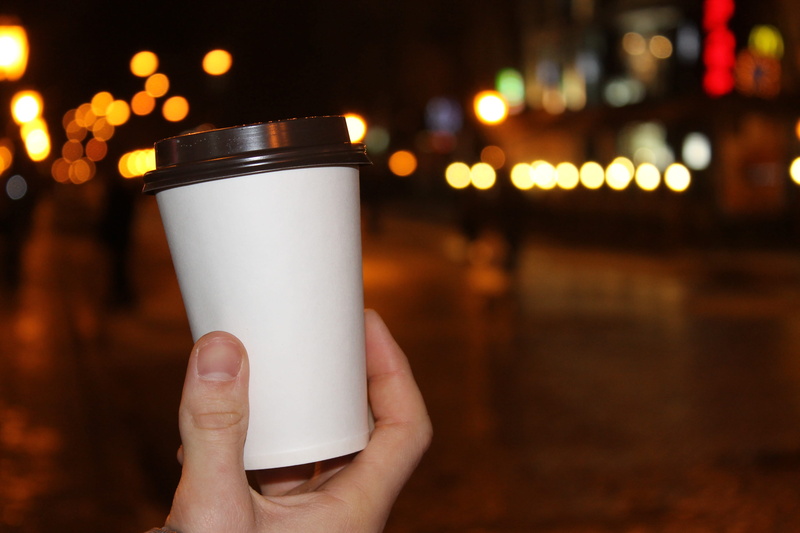 body part, milk, Cup, hand, alcohol, outdoors, boulevard, human body part, street, refreshment, architecture, Evening, Night, human limb, holding, focus on foreground