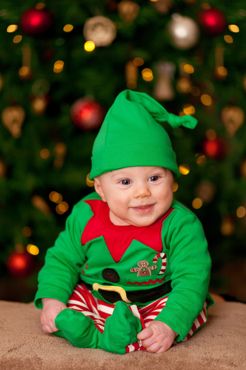 green color, innocent, looking at camera, Baby, happy, smiling, baby, wearing, Child, Christmas, elf, santa hat, people, boy, indoors, sitting, smile, home Interior