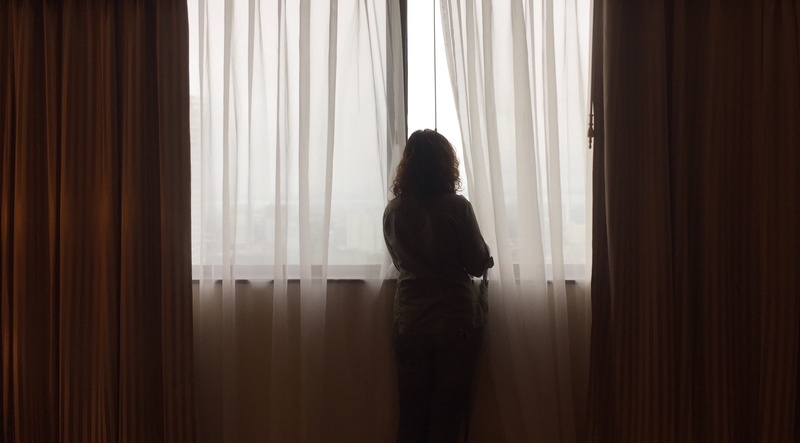 one person, curtain, emotion, indoors, content, inside, depression - sadness, adult, watcher, lifestyles, hotel, lone, lonely, rear view, standing, person