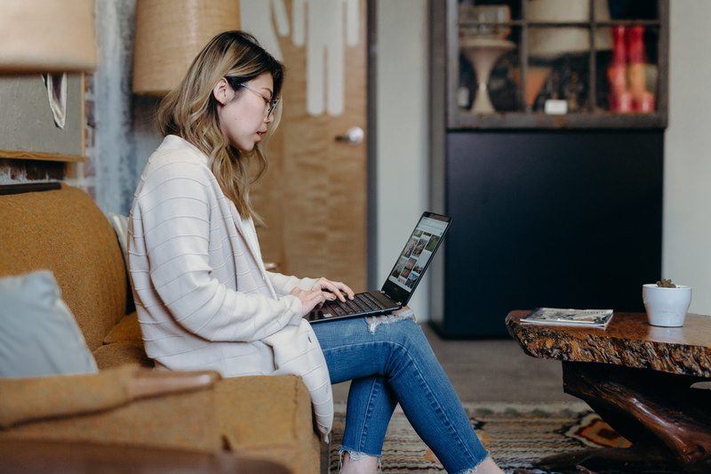 indoors, pants, casual clothing, lcd screen, 5K, electronics, communication, sitting, hairstyle, one person, sofa, lifestyles, computer, looking, looking down
